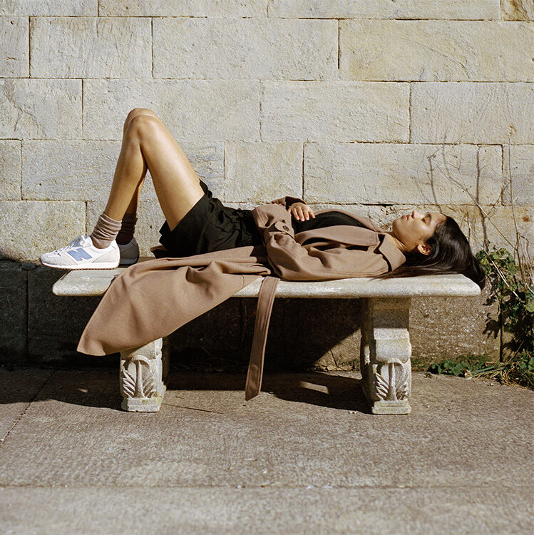A woman wearing the 471 lies on a stone bench 