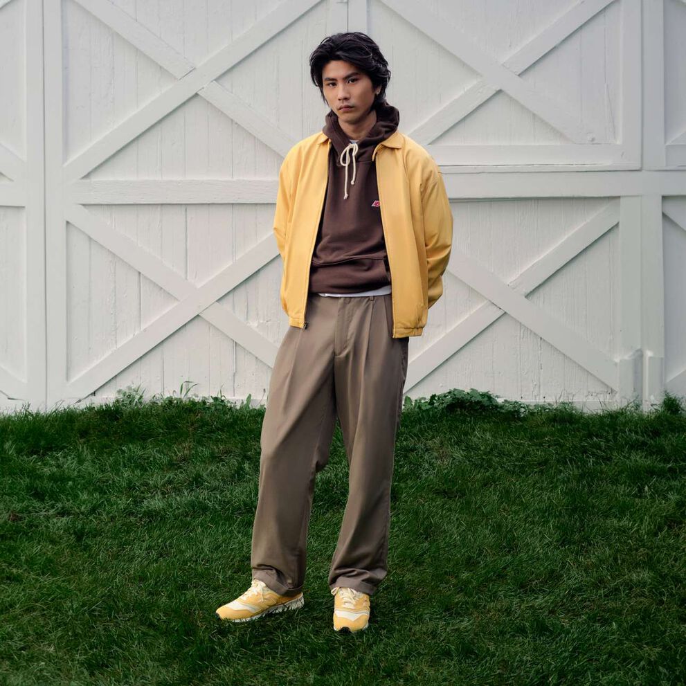 A man standing in front of a barn wearing New Balance shoes.