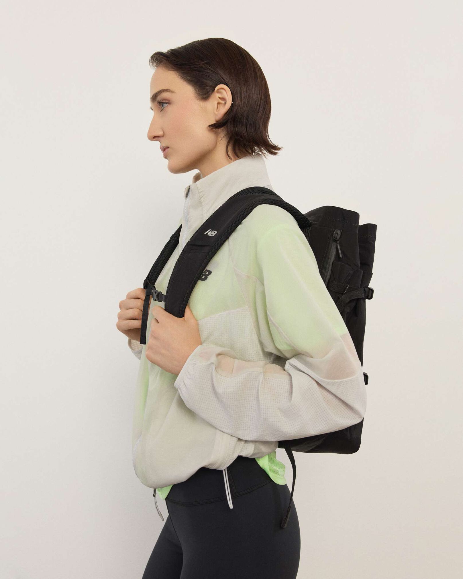 A woman wearing New Balance standing in front a white wall.