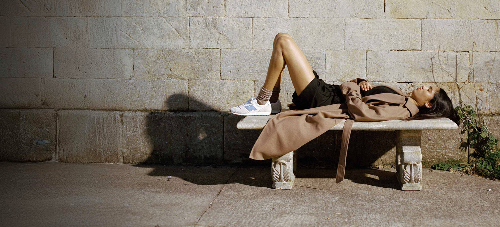 A woman wearing the 471 lies on a stone bench 