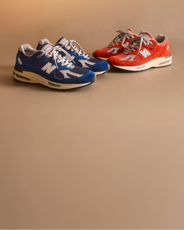 Two pairs of New Balance Made in UK sneakers in a beige studio environment. 