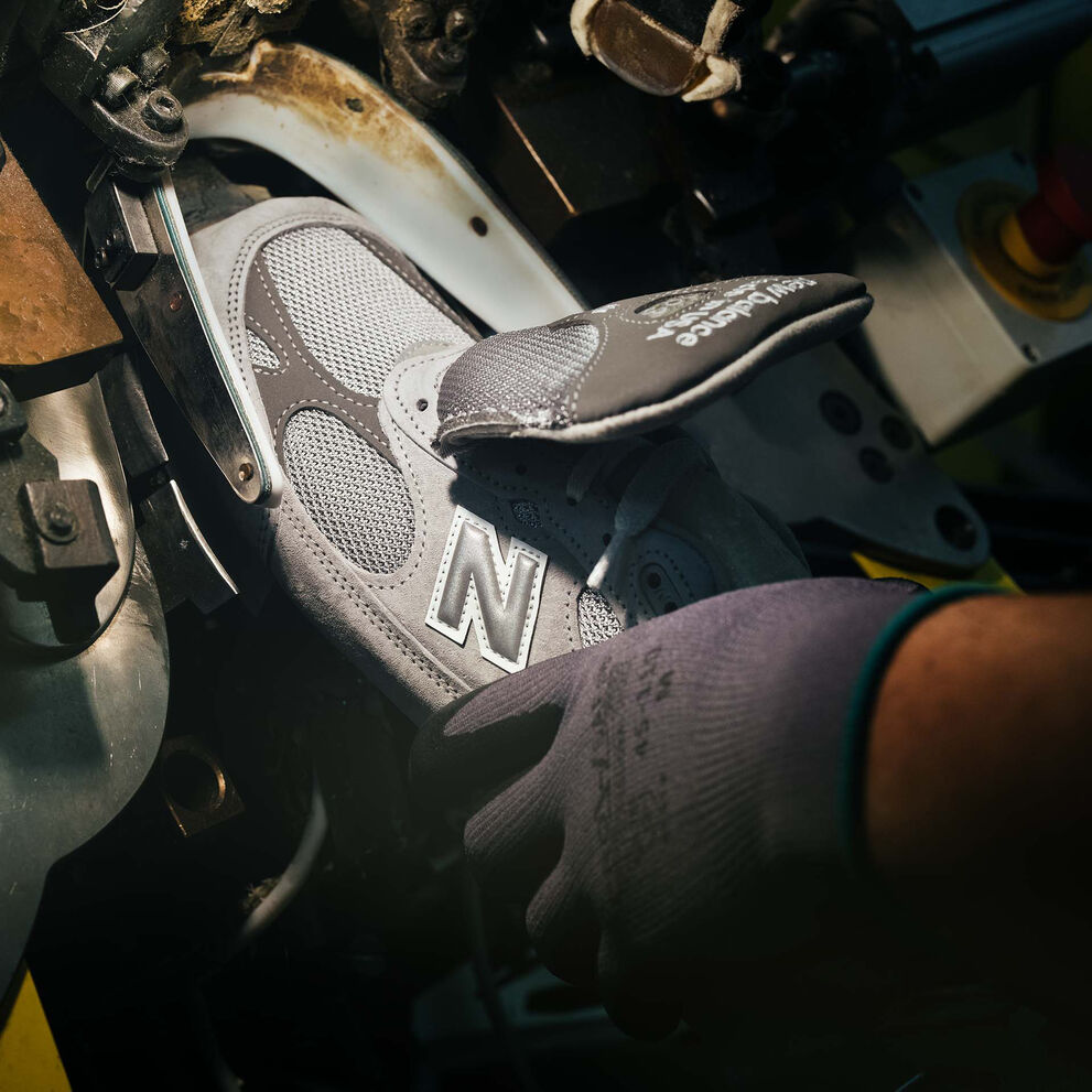 A hand putting a sneaker into a machine during its construction.